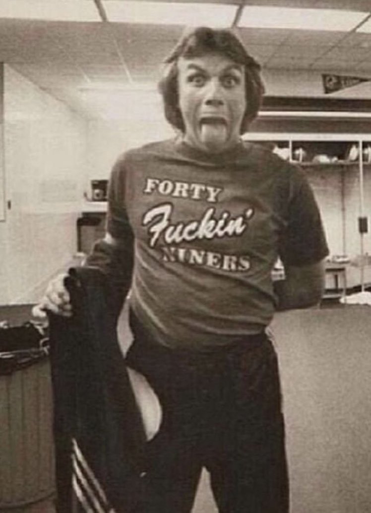 a man in a t - shirt is standing in an office