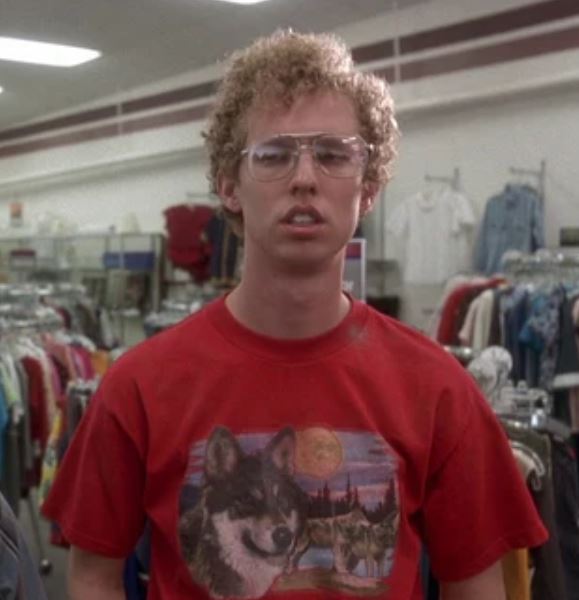 A man wearing a red t-shirt with a wolf graphic stands in a clothing store.