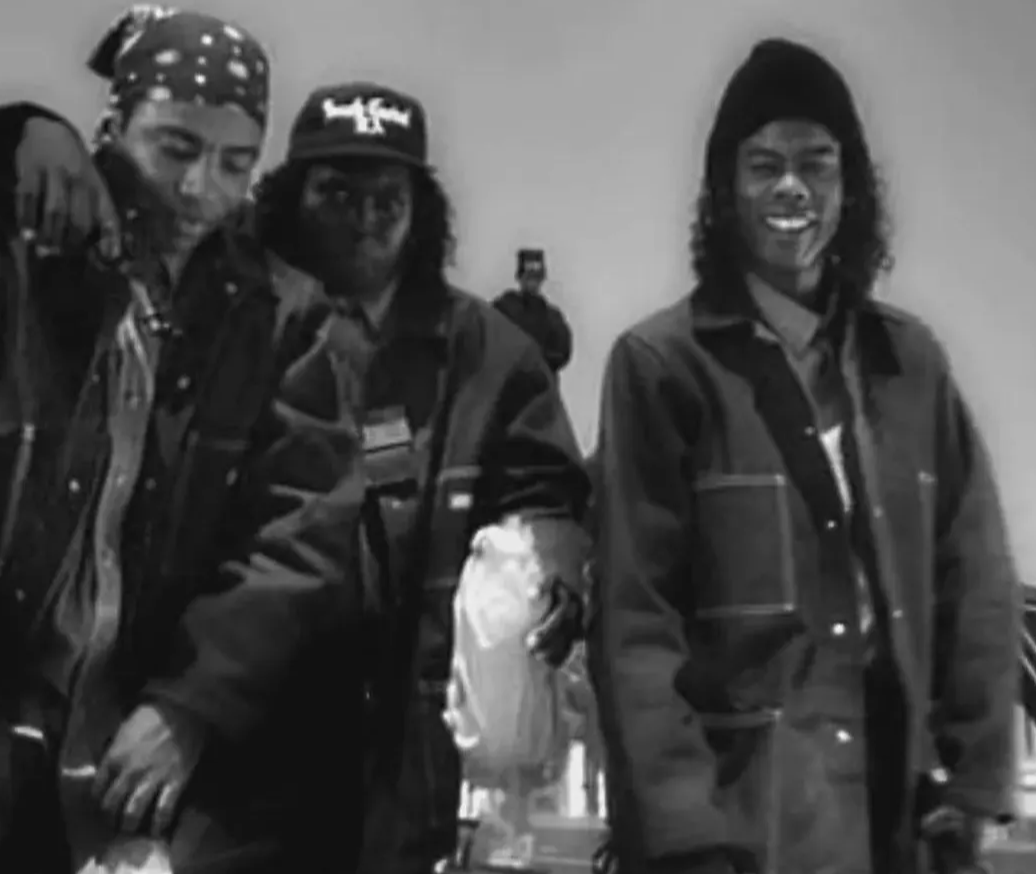 A black and white image showing three people, two men and one woman, standing together and smiling.