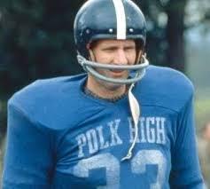 A man wearing a blue football jersey with the text "Polk High" on it, standing outdoors.